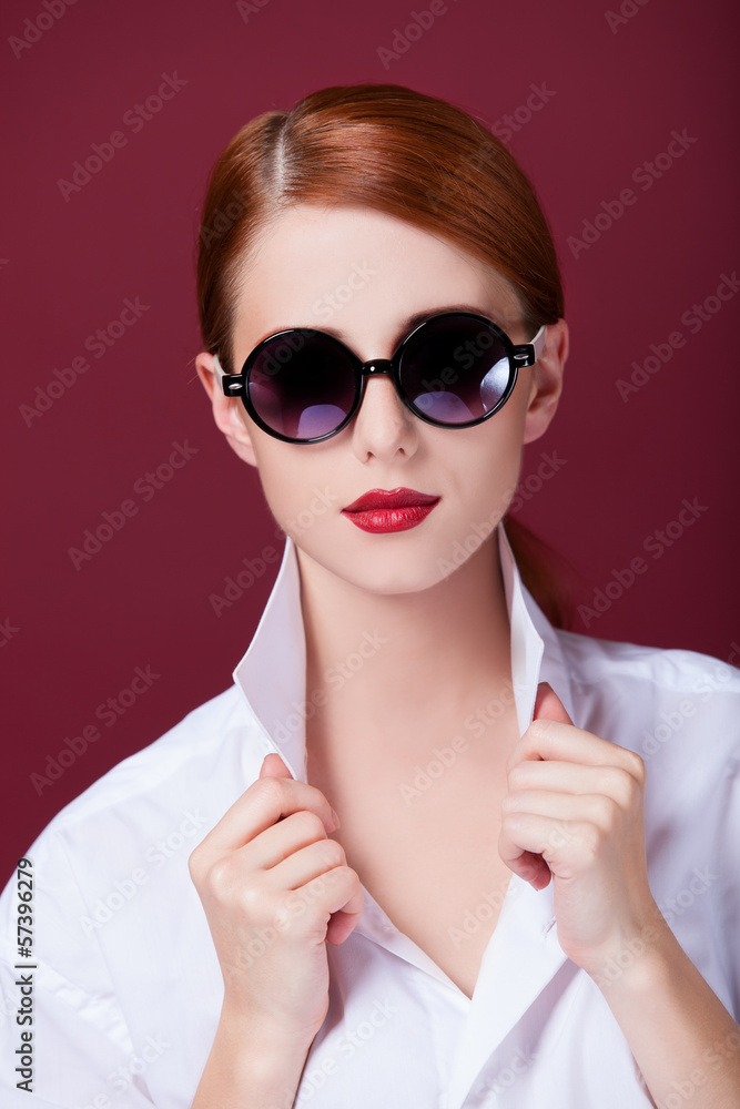 Redhead in sunglasses on red background Redhead in sunglasses on red background