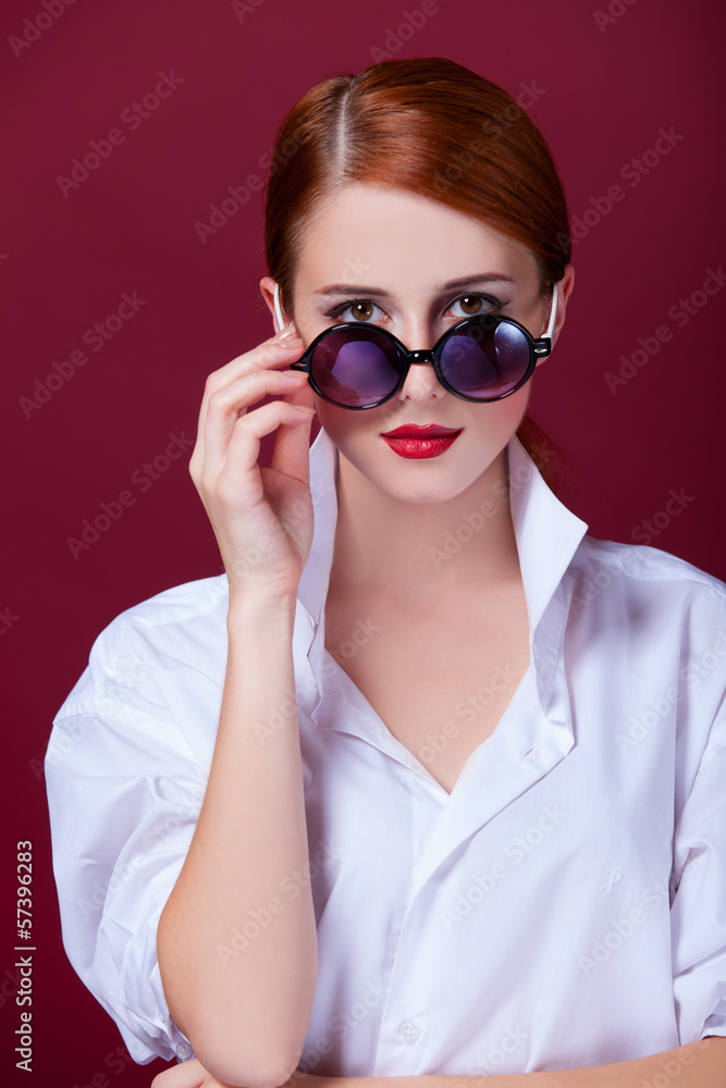 Redhead in sunglasses on red background Redhead in sunglasses on red background