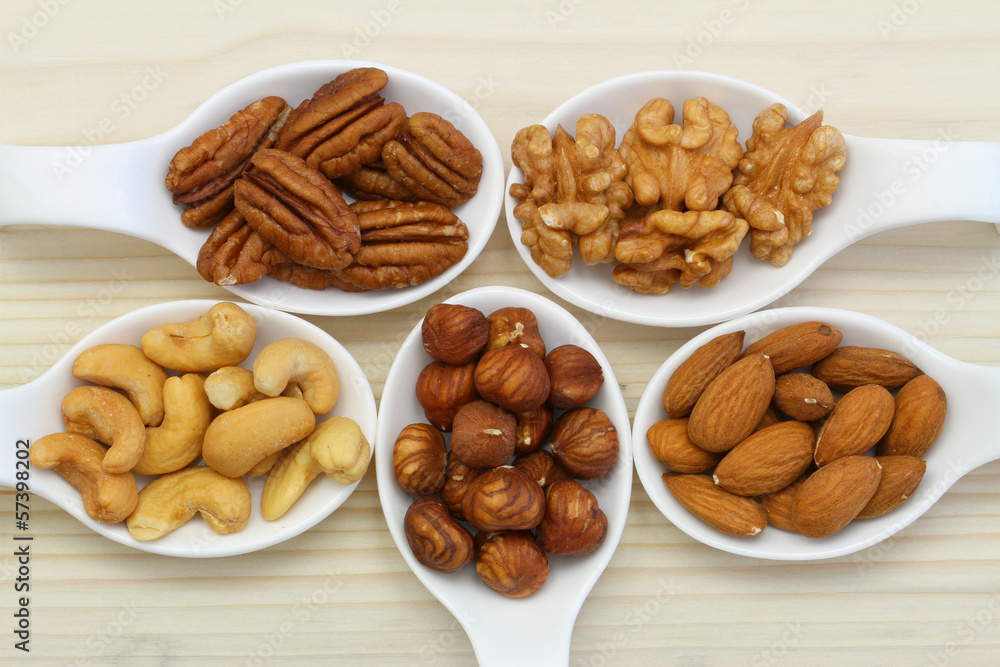Selection of nuts on white porcelain spoons Selection of nuts on white porcelain spoons