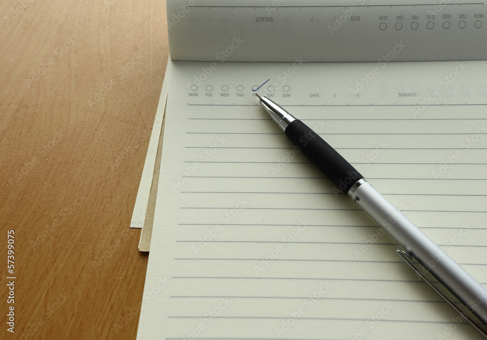 Pen and business plan notebook on wooden desk