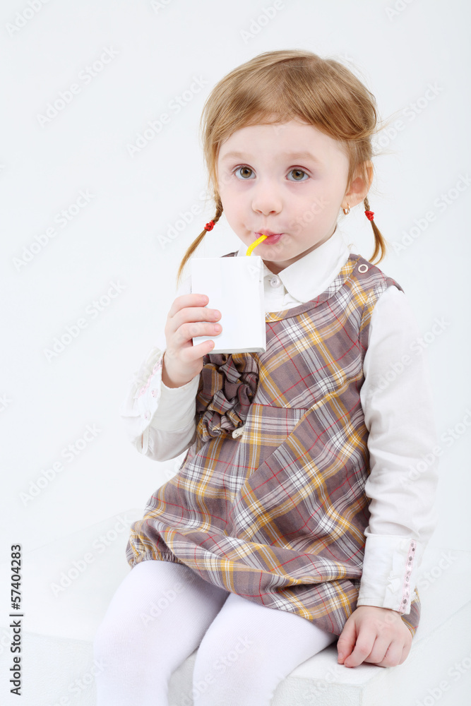 Little cute girl sits and drinks sweet juice on white background Little cute girl sits and drinks sweet juice on white background