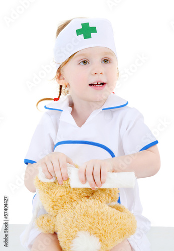 Little girl dressed as nurse bandages head to toy rabbit photo