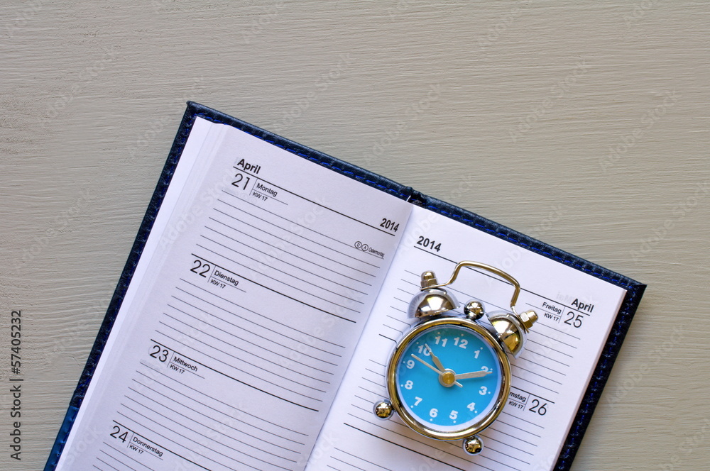 terminkalender mit blauem wecker auf holztisch terminkalender mit blauem wecker auf holztisch