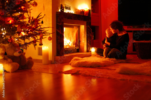 Young mother and her daughter by a fireplace