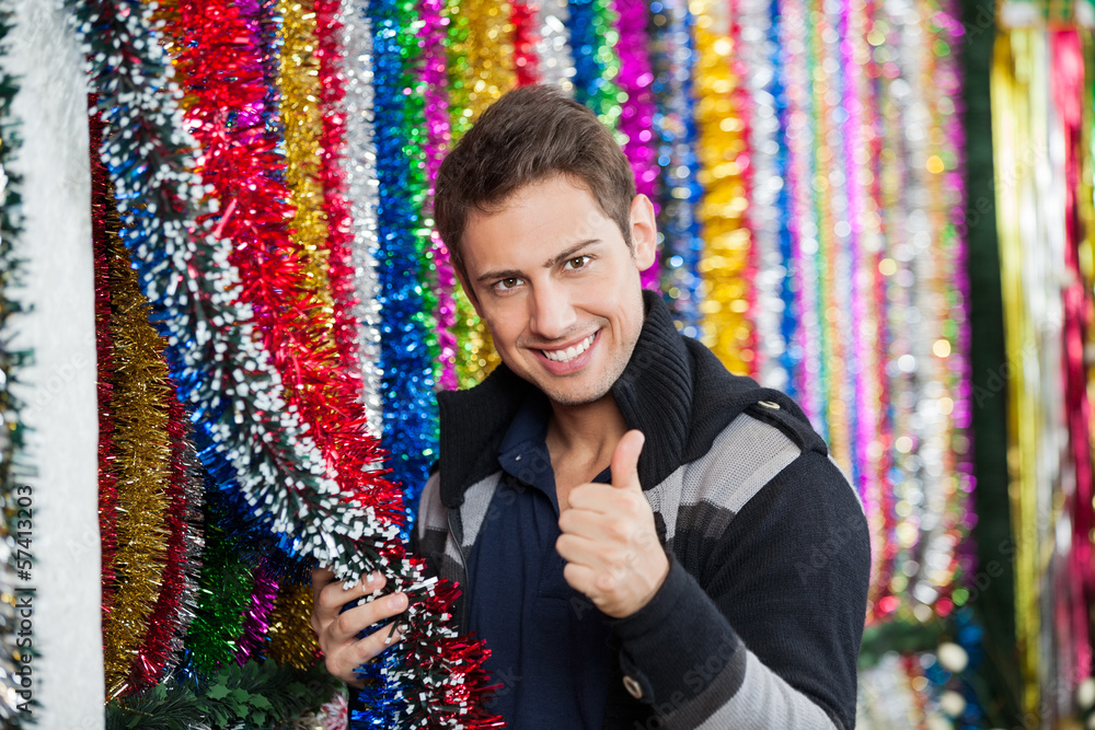 Man Gesturing Thumbs Up While Holding Tinsels At Store
