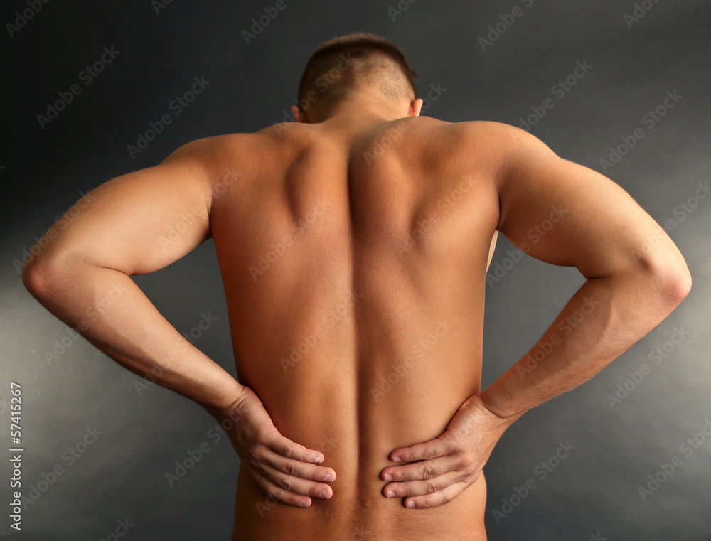 Fototapeta premium Young man with back pain on grey background