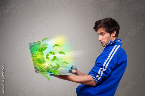 Casual boy holding laptop with recycle and environmental symbols