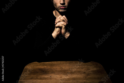 Man praying in the dark at table