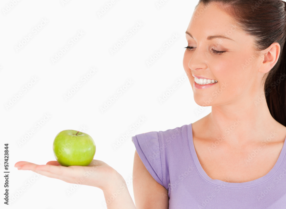 Charming woman holding an apple while standing Charming woman holding an apple while standing