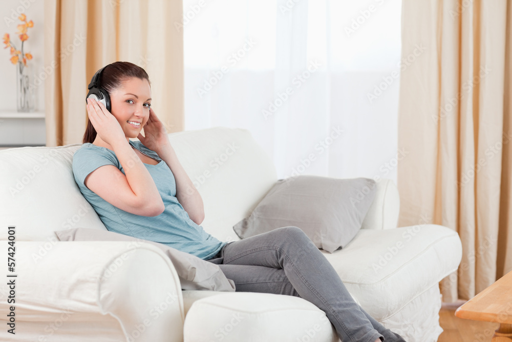 Beautiful woman relaxing with headphones while sitting on a sofa Beautiful woman relaxing with headphones while sitting on a sofa