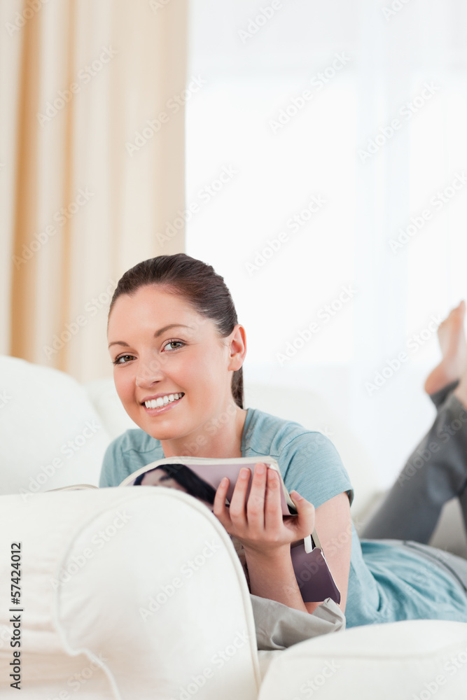 Attractive woman reading a magazine while lying on a sofa Attractive woman reading a magazine while lying on a sofa