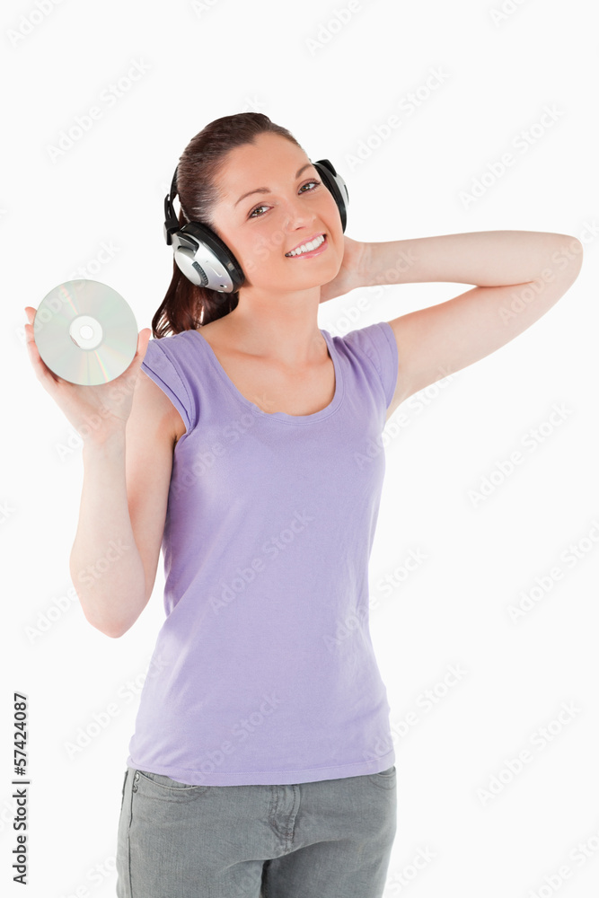 Pretty woman with headphones holding a CD while standing Pretty woman with headphones holding a CD while standing