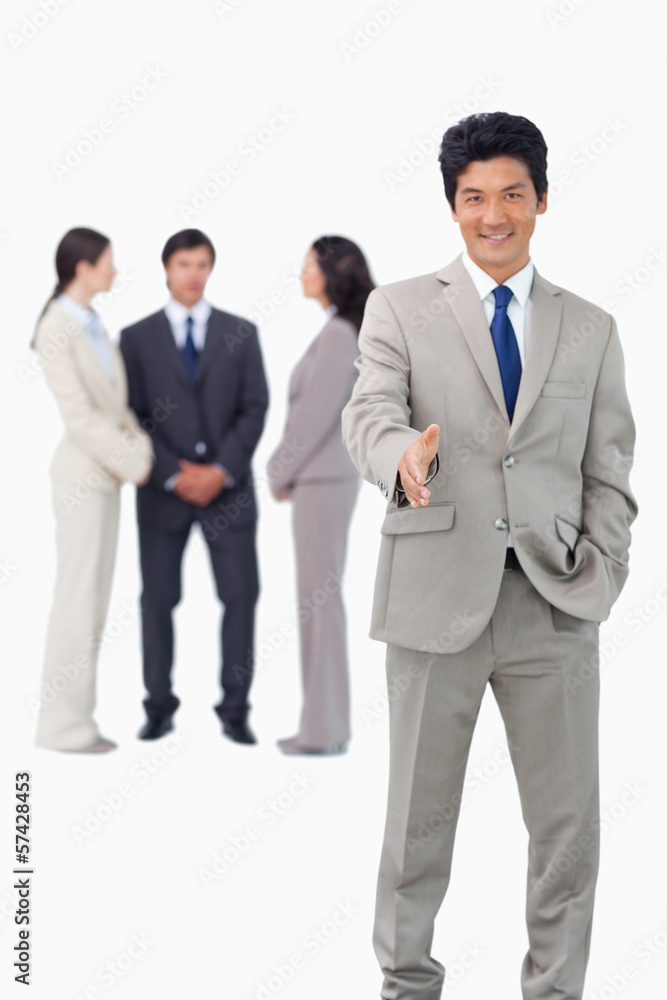 Salesman with team behind him offering hand Salesman with team behind him offering hand