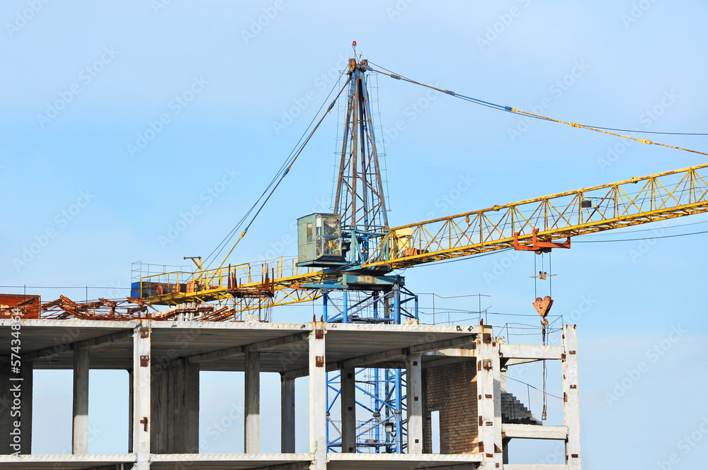 Crane and building construction site against blue sky