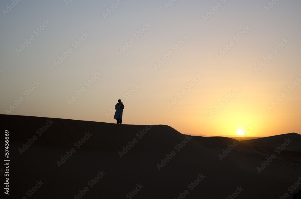 Moroccan desert sunset with Bedouin in the distance