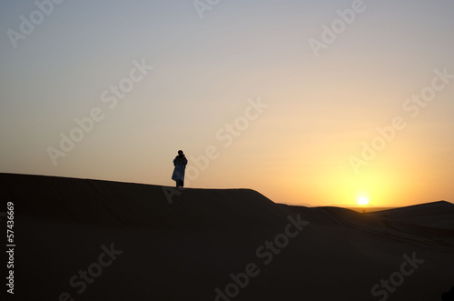 Moroccan desert sunset with Bedouin in the distance