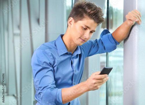 Happy young businessman reading emails from a smart phone