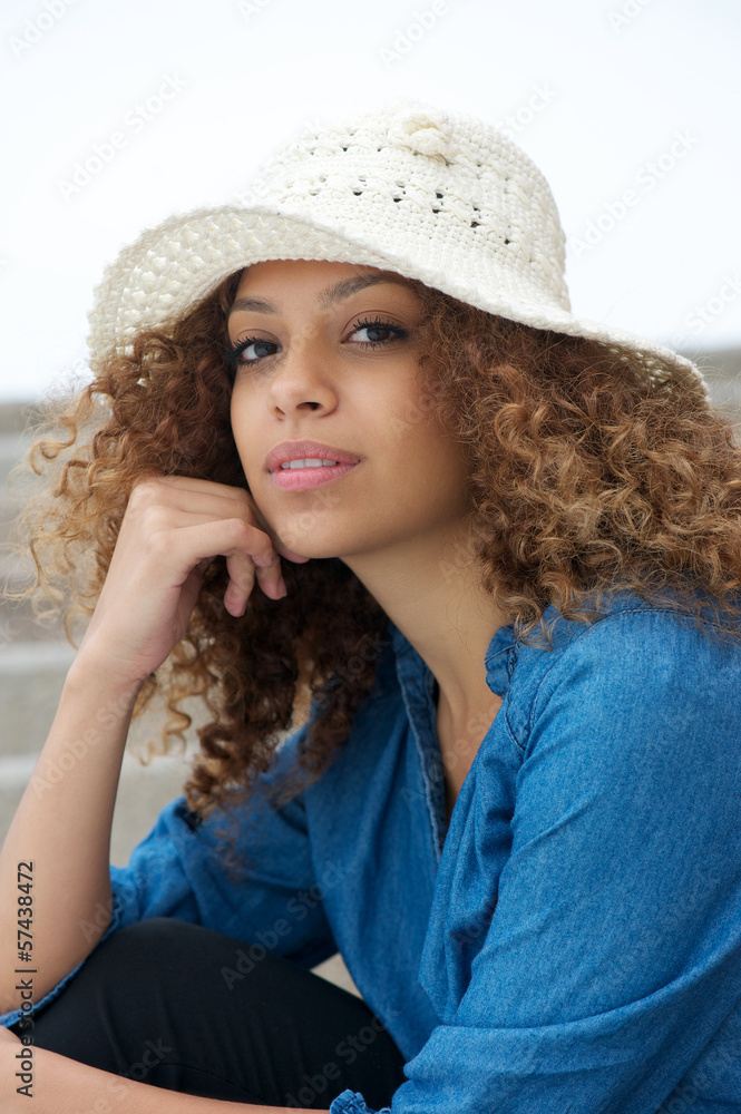 portrait of an attractive young woman sitting outdoors with hat portrait of an attractive young woman sitting outdoors with hat