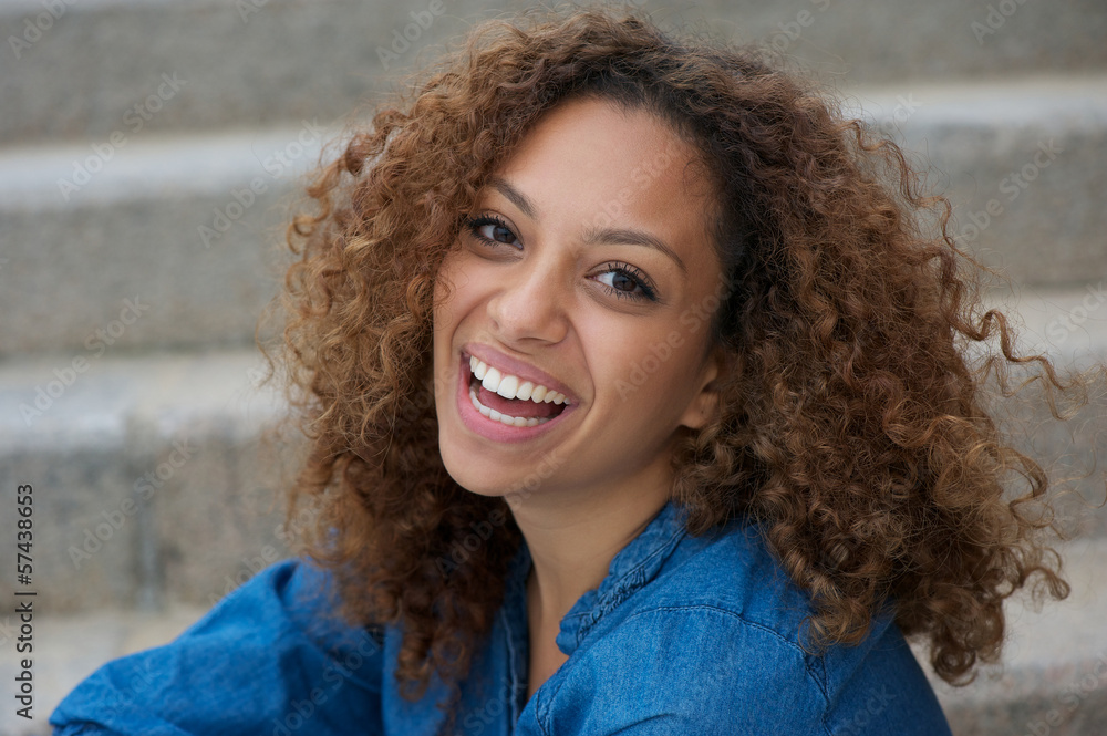 Beautiful young woman with curly hair smiling outdoors Beautiful young woman with curly hair smiling outdoors