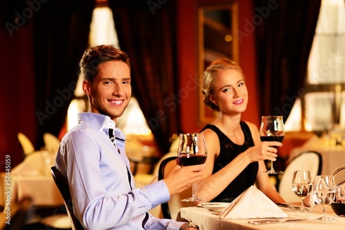 Beautiful young couple with glasses of red wine