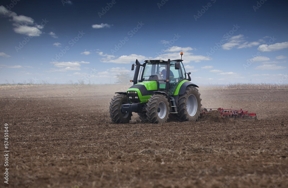 Obraz premium Young farmer in tractor preparing land for sowing