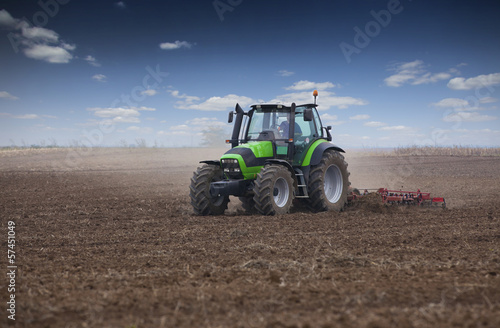 Young farmer in tractor preparing land for sowing