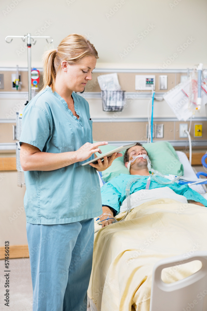 Nurse Using Digital Tablet While Patient Resting On Bed Nurse Using Digital Tablet While Patient Resting On Bed