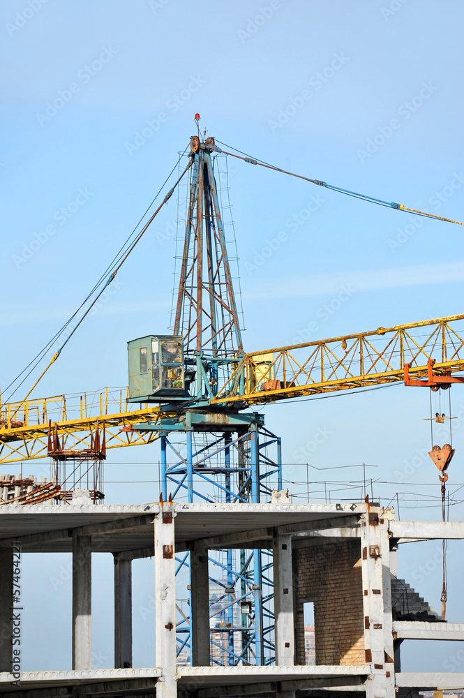 Crane and building construction site against blue sky