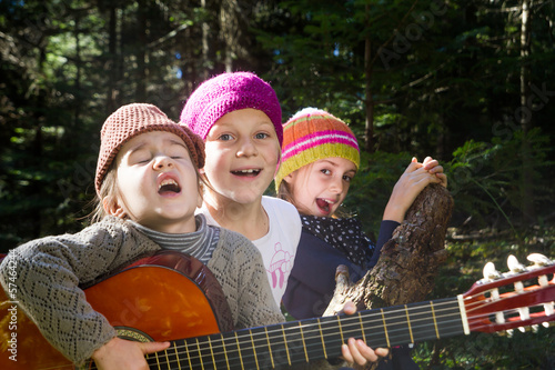 Group of children singing and playing guitar together in the for