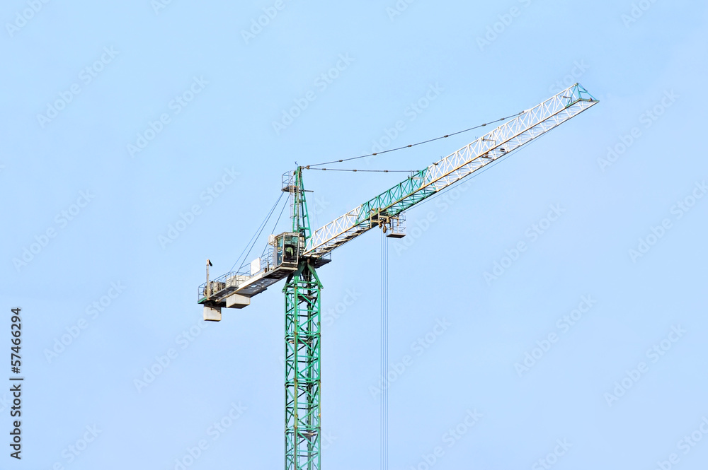Green construction tower crane against blue sky Green construction tower crane against blue sky