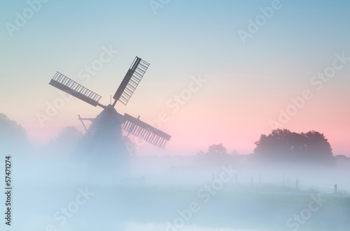 charming Dutch windmill in dense sunrise fog