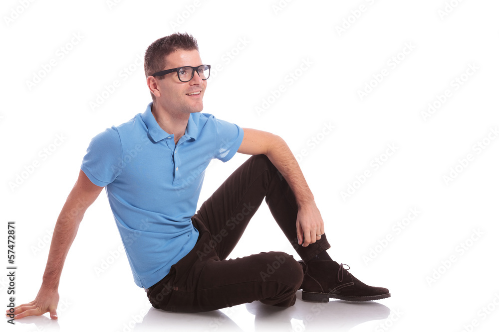casual man smiles while sitting on the floor casual man smiles while sitting on the floor