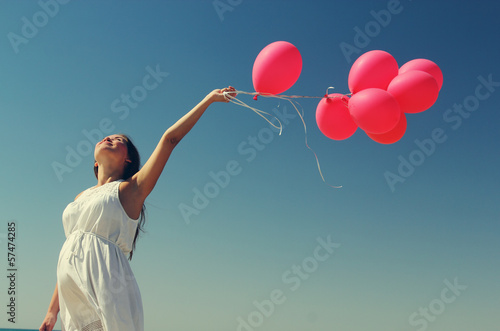 Young pregnant woman holding red balloons. Photo in old color im © dubova