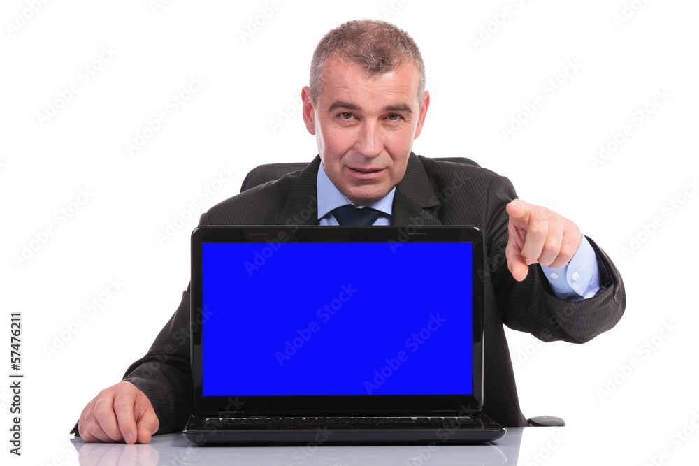 business man with laptop on desk points at you business man with laptop on desk points at you