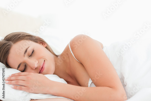 Woman lying in bed asleep smiling softly