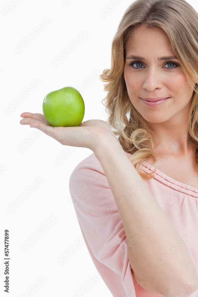 Young woman holding a green apple while looking at the camera Young woman holding a green apple while looking at the camera