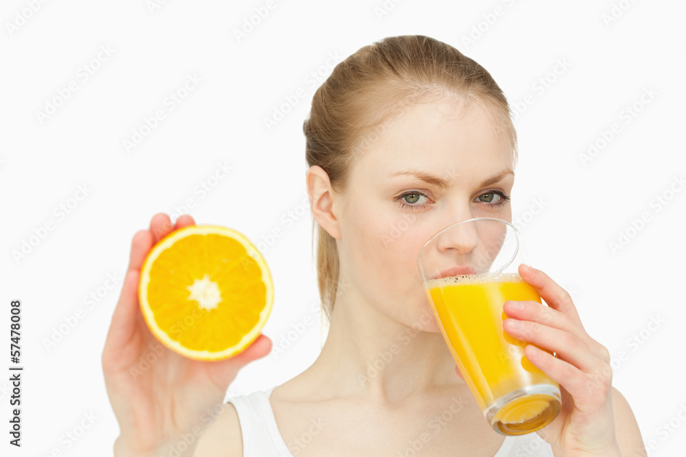 Woman presenting an orange while drinking Woman presenting an orange while drinking