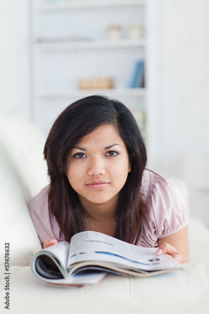Woman holding a magazine while resting on a couch Woman holding a magazine while resting on a couch