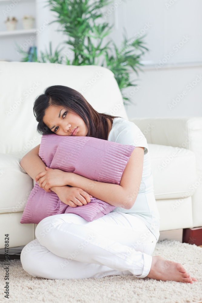 Woman looking sad while holding a pillow Woman looking sad while holding a pillow