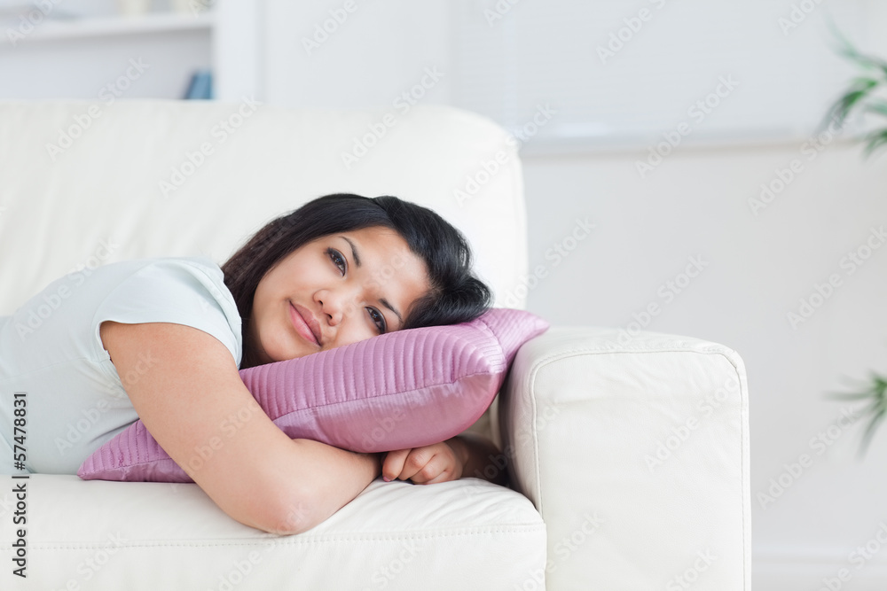 Woman relaxing on a sofa while holding a pillow Woman relaxing on a sofa while holding a pillow
