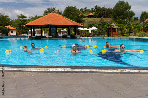 group doing aqua aerobics in swimming pool with dumbbells