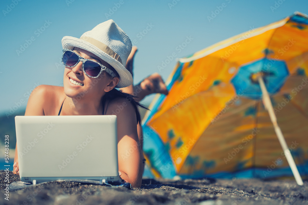 Obraz premium happy smiling girl is sunbathing with laptop