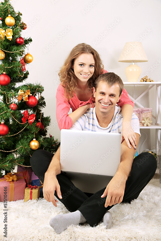 Happy young couple near Christmas tree at home