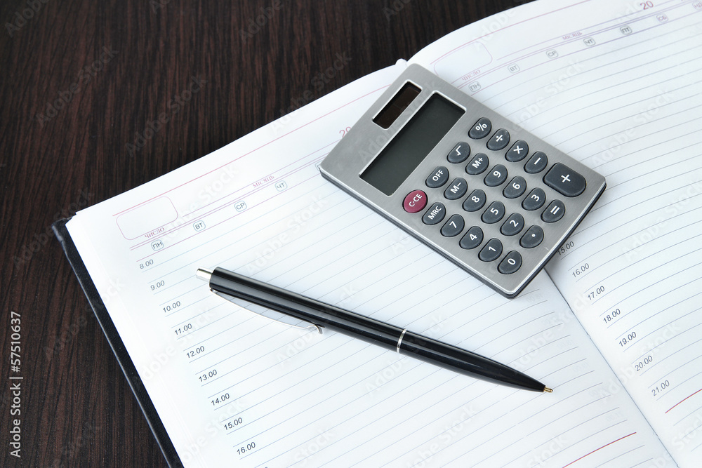 Notebook with pen and calculator on wooden background Notebook with pen and calculator on wooden background