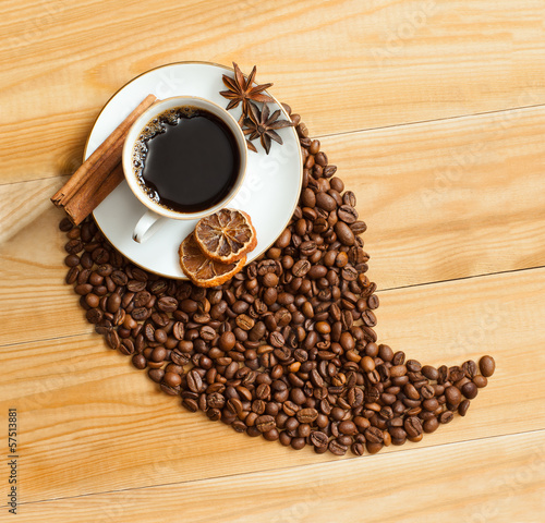A cup of coffee and coffee beans on wooden surface