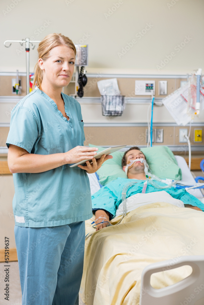 Nurse With Digital Tablet While Male Patient Resting On Bed Nurse With Digital Tablet While Male Patient Resting On Bed
