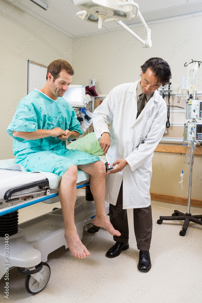Fototapeta premium Doctor Examining Patient's Knee With Hammer In Hospital