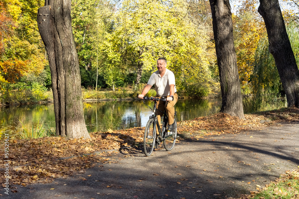 Obraz premium Man rides his bike through the park in autumn