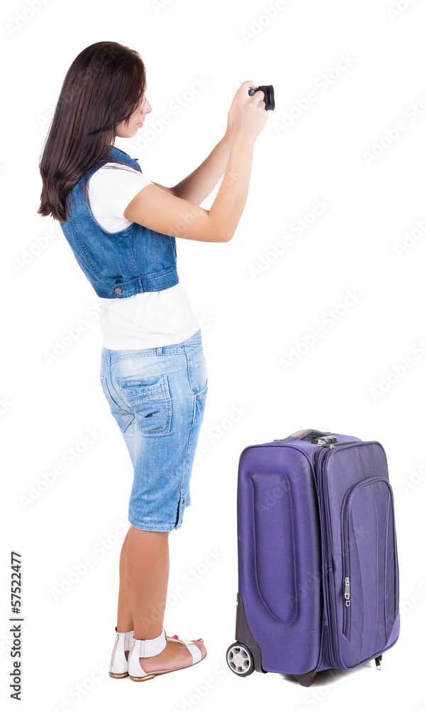 Back view of woman photographing traveling with suitcas.