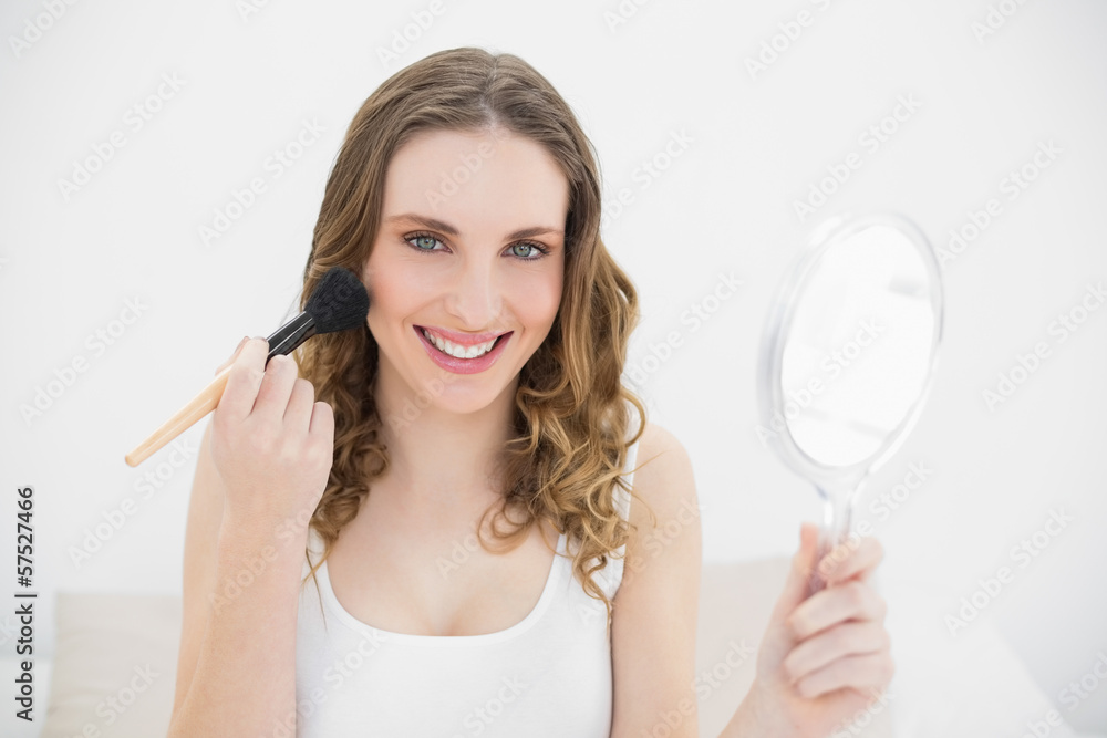 Happy woman putting powder on her cheeks Happy woman putting powder on her cheeks